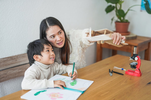 亚洲母亲和孩子在一起玩的时间在家里与木头飞机，而做绘画活动图片下载