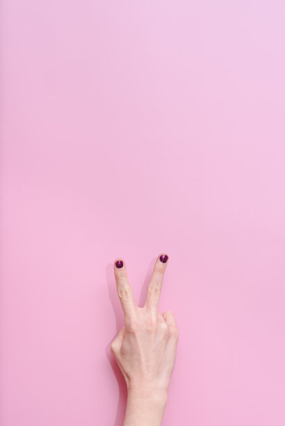 在粉红色的背景下，一名白人妇女的手伸出手指数两下图片下载