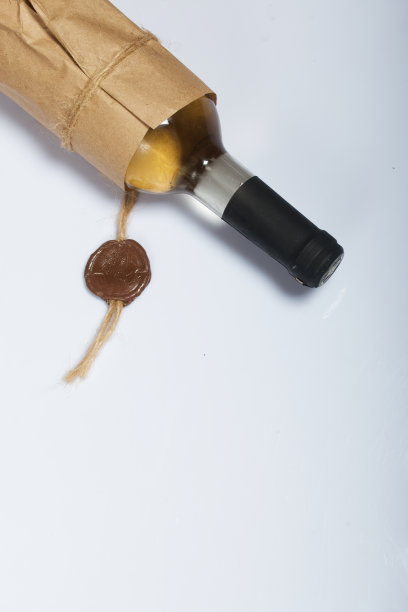 酒精瓶。包裹在纸上。在白色的表面上。图片下载
