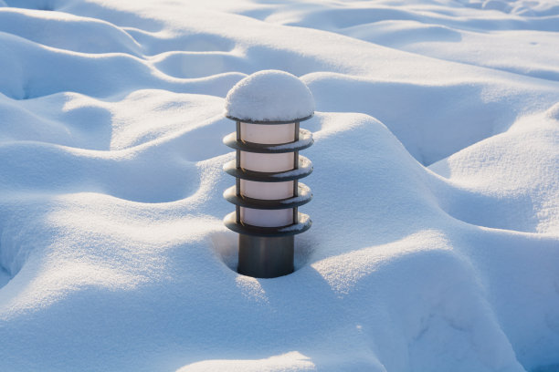 一盏地面公园的灯从雪堆中伸出来，在阳光的照耀下非常美丽图片下载