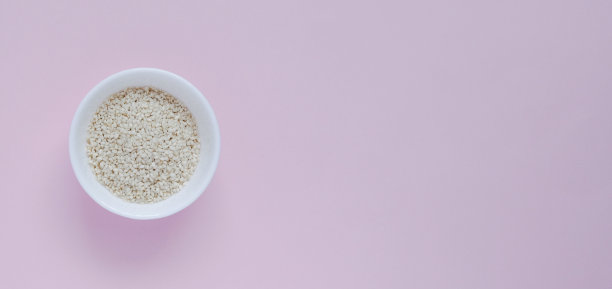 白色的芝麻，在一个小杯子里，在粉红色的背景上图片下载