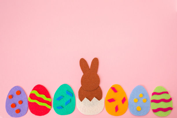 剪出彩色蛋的毛毡应用，从蛋中孵出棕色的兔子。粉红色的背景。平的。复活节装饰品。本空间图片下载