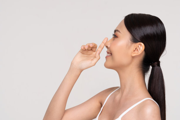 美丽的亚洲女人触摸鼻子微笑，干净和新鲜的皮肤，快乐和愉快的白色情绪，整形鼻子，美容化妆品和spa面部治疗的概念图片下载