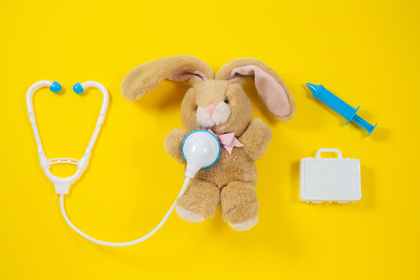 养护一只兔子。黄色背景上的玩具医疗设备。图片下载