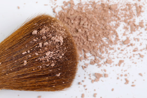 散乱的棕褐色的面部散粉和化妆刷隔离在白色的背景上。图片下载