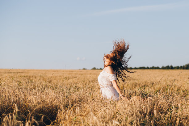 一个长卷发的女孩在麦田里摆姿势图片下载