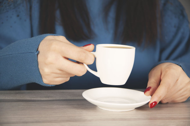 女人把一杯咖啡放在桌子上图片下载