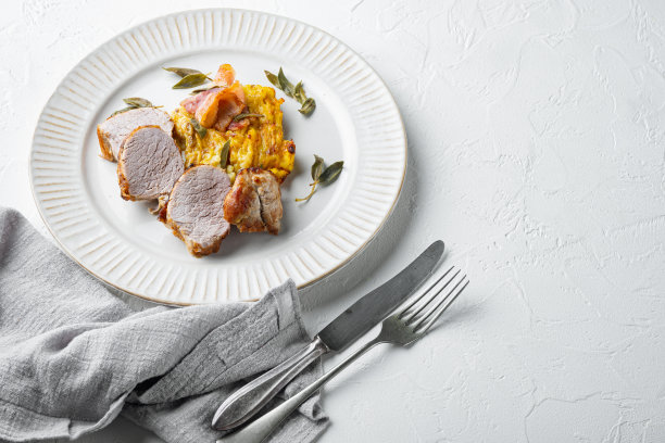 烤猪里脊配土豆泥，鼠尾草和意大利熏火腿，在盘子上，在白色的石头背景，有copyspace和文字空间图片下载