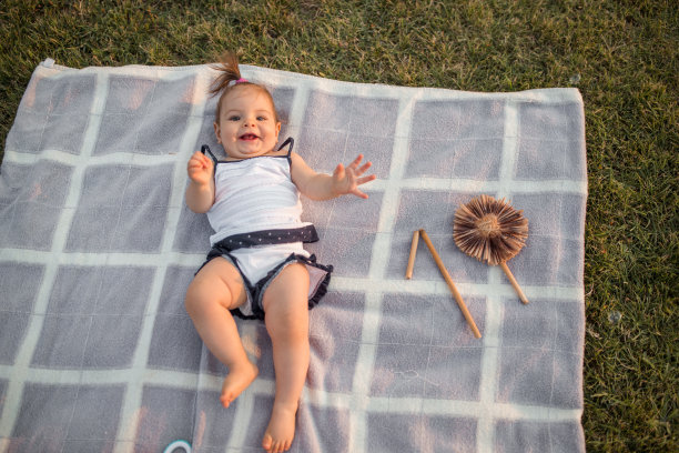 小女孩躺在公园的毯子上图片下载