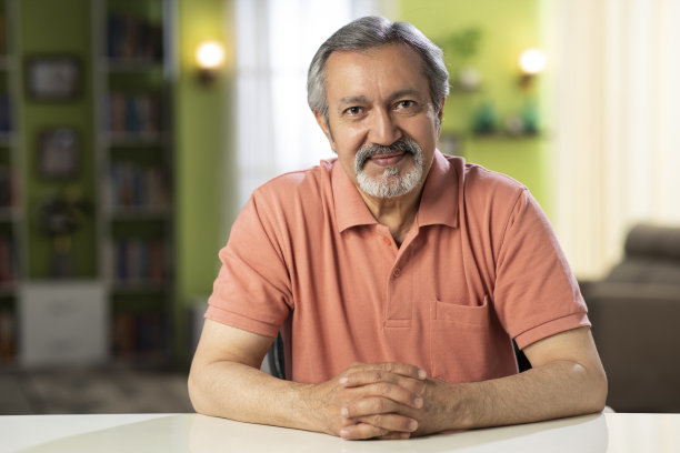 一个成熟男人坐在家里的椅子上的照片:-库存照片图片下载