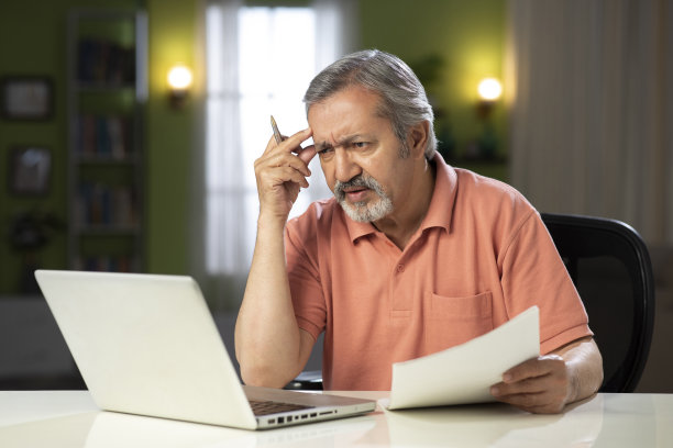 一个成熟男人坐在家里的椅子上的照片:-库存照片图片下载