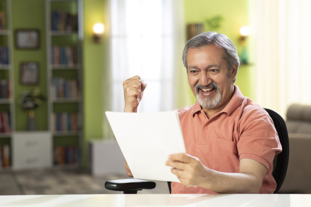 一个成熟男人坐在家里的椅子上的照片:-库存照片图片下载