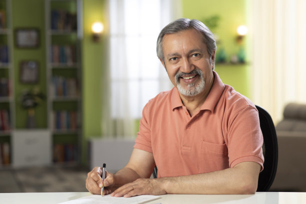 一个成熟男人坐在家里的椅子上的照片:-库存照片图片下载