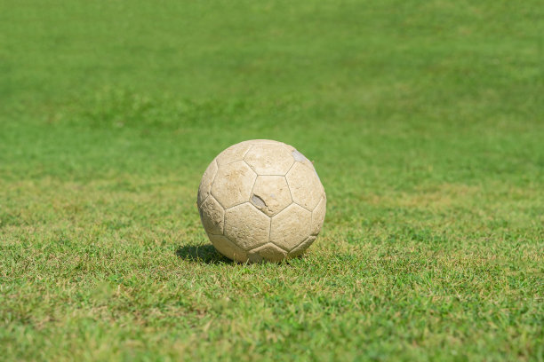 旧的足球在绿色的草地上。图片下载