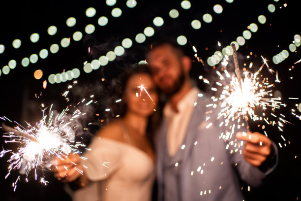 关注火花。新婚夫妇在晚上的公园里戴着花环图片下载