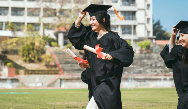 快乐毕业的同学们拿着毕业证书，在学校的体育馆里奔跑图片下载