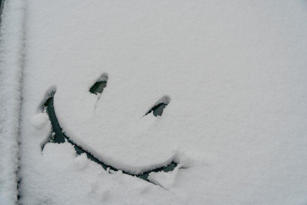 雪的背景。纹理湿雪与一个愉快的笑脸符号图案在冬季车窗外的汽车特写。微笑在雪中，幸福开朗的形象。冬天的时间概念图片下载