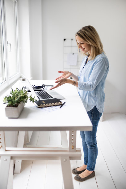 在符合人体工程学的站立式办公桌前工作的女商人图片下载