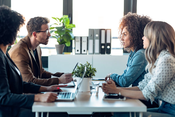 几岁以上的商务人士在办公室里一边用笔记本电脑工作一边谈论他们的新项目。图片下载