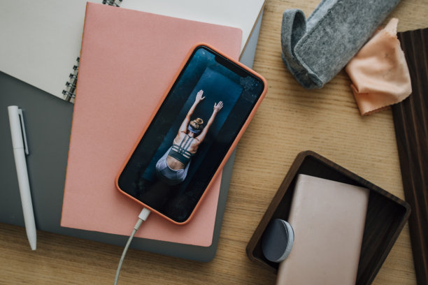 隔离期间的专注可能具有挑战性:一张在忙碌的办公桌上，一个不认识的女人在手机屏幕上做瑜伽的照片图片下载