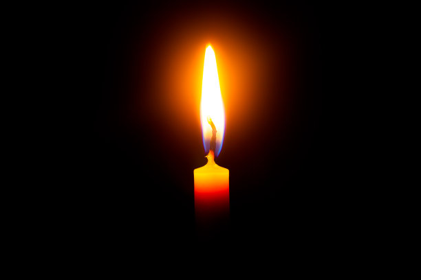 靠近单蜡烛光和火焰在黑色的背景图片下载
