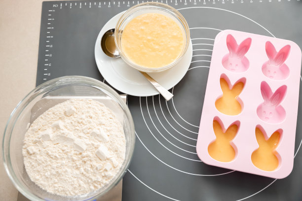 烘焙用具和配料。将生面团展开成硅胶杯形蛋糕模具以制作自制蛋糕的过程。图片下载