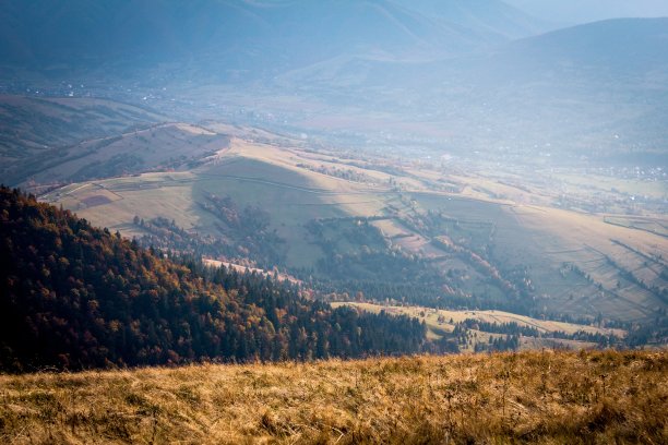 山的风景。从山顶俯瞰山谷中的村庄。照片在金色的秋天与薄雾。图片下载