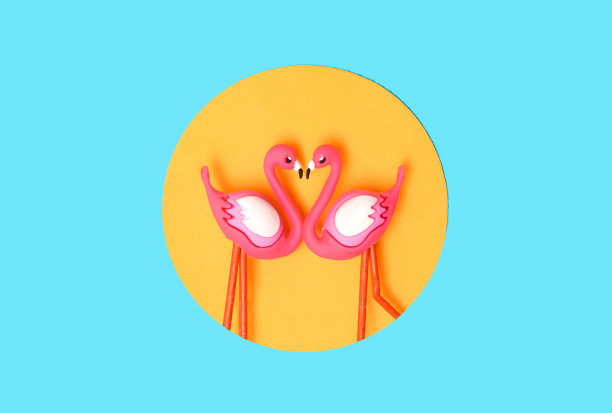 图案创建的两个火烈鸟玩具在橙色圆圈在霓虹灯蓝色的背景。前视图。图片下载