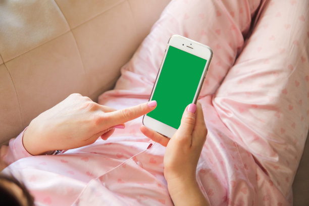 一个在家里沙发上用智能手机购物或存钱的不可思议的女人。图片下载