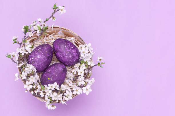 紫罗兰色的复活节彩蛋装在篮子里，花在紫罗兰色的背景上。水平的照片。俯视图图片下载
