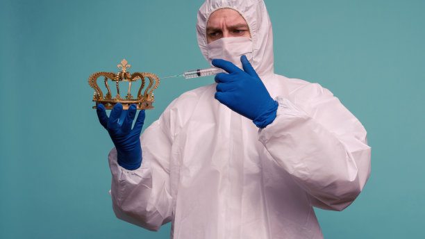 一位男医生穿着防护服，戴着面罩，在牙冠上注射。冠状病毒防护理念。图片下载
