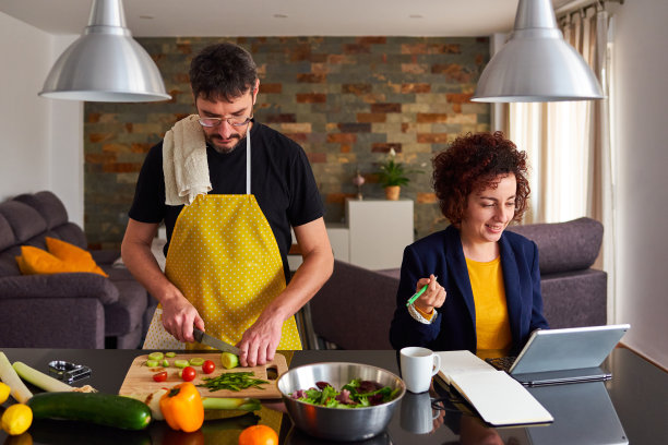 年轻夫妇远程工作和做饭图片下载