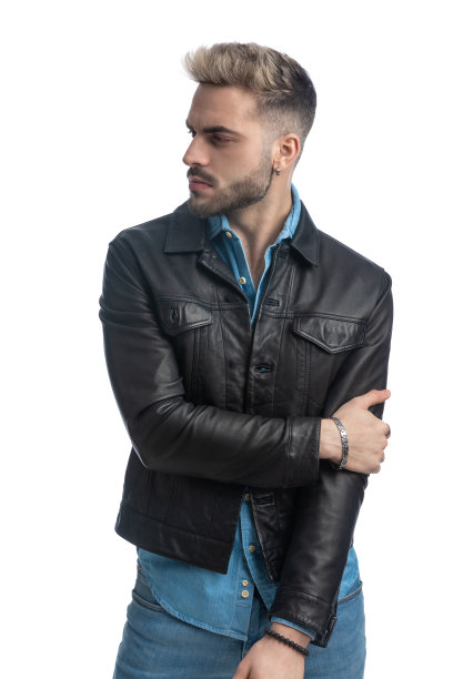 有吸引力的胡子男子在皮夹克看向一边和摆姿势图片下载
