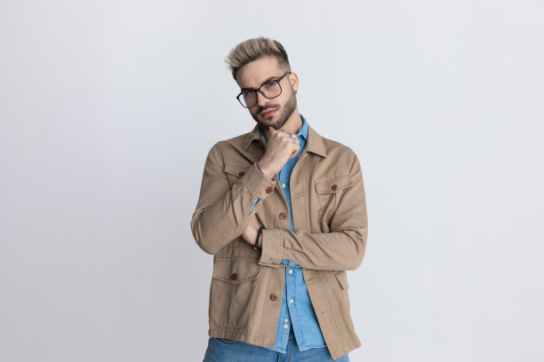 体贴的年轻人在牛仔衬衫手扶着下巴和思考图片下载