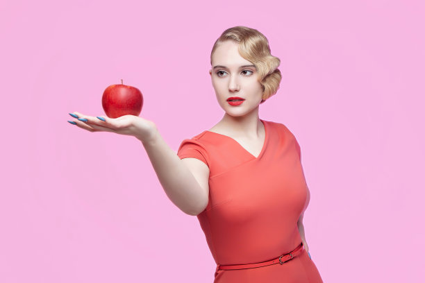 年轻迷人的金发美女，有着复古的发型，手里拿着一个红苹果图片下载