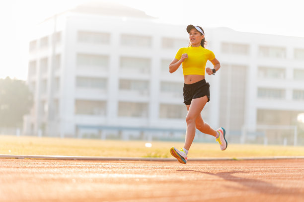 一个女人在阳光明媚的早晨在体育场的跑道上跑步图片下载