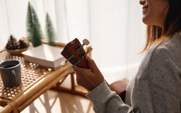 一位年轻女子喜欢在家弹奏尤克里里琴图片下载