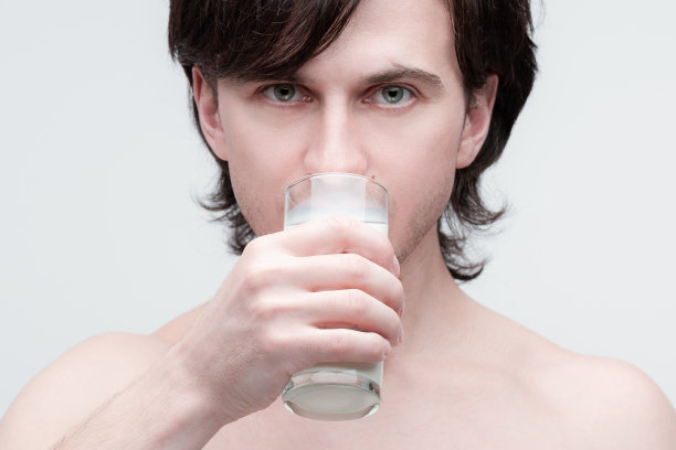 特写照片英俊的年轻白人男子喝牛奶从一个杯子。图片下载