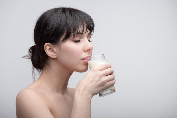 年轻女子喝牛奶的美丽镜头。图片下载