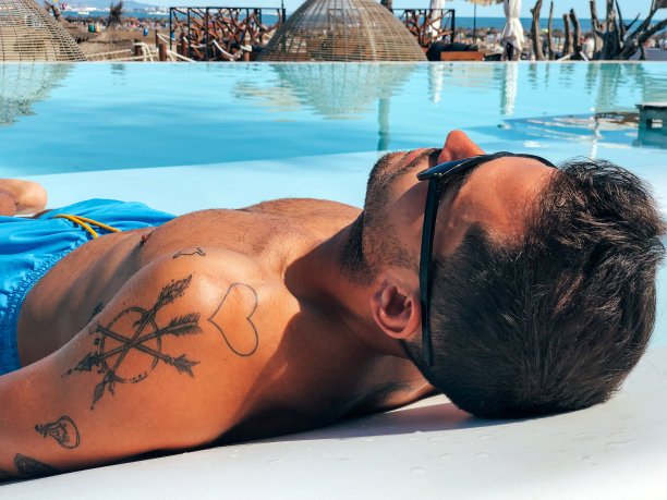 在泳池边的躺椅上休息的男人图片下载