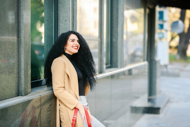 一个美丽微笑的年轻白人女人的画像在街上。城市/城市街道照片。图片下载