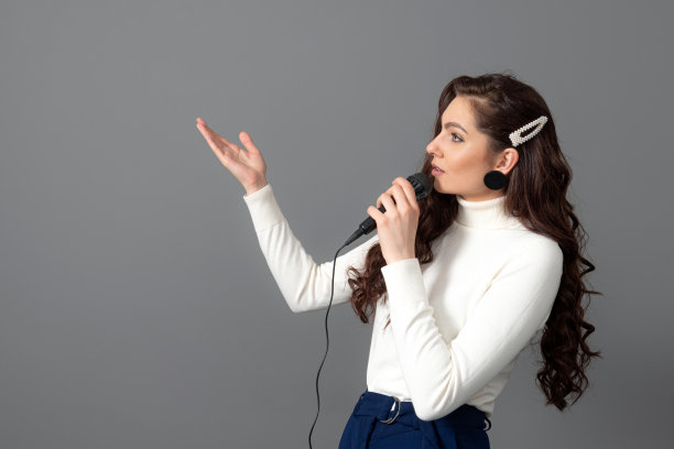 有魅力的女演讲者在演讲时，手持麦克风并做一些手势图片下载