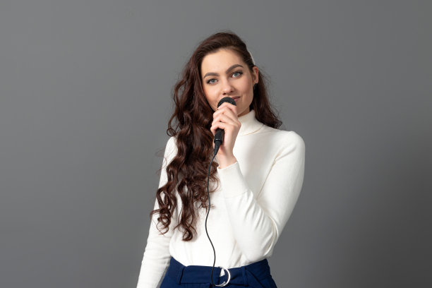 一位迷人的女会议发言人在演讲时，手持麦克风，做一些手势图片下载