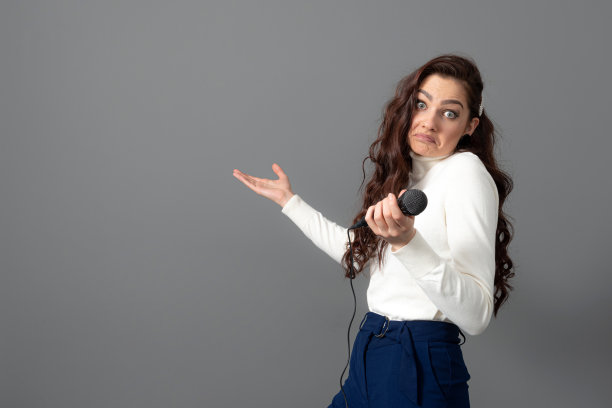 有魅力的女演讲者在演讲时，手持麦克风并做一些手势图片下载