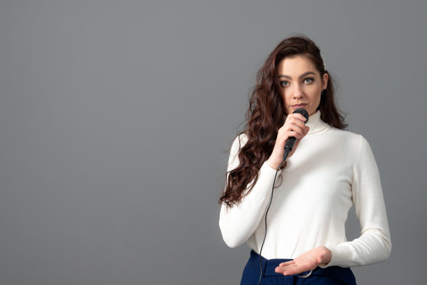 有魅力的女演讲者在演讲时，手持麦克风并做一些手势图片下载
