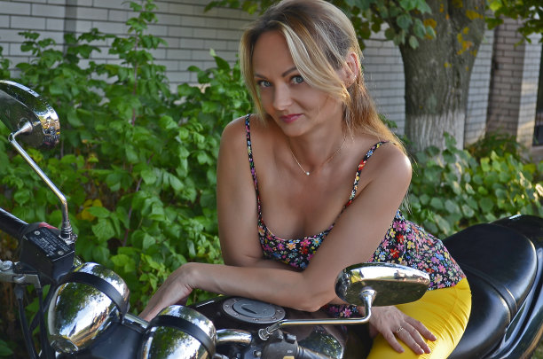 美丽的成年女子开着一辆经典的摩托车。图片下载