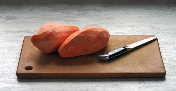 去皮的甘薯根用刀放在砧板上。图片下载