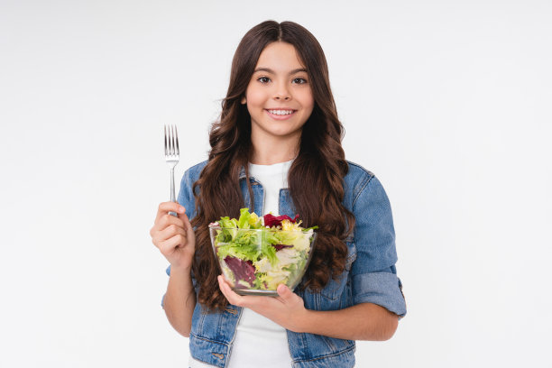 欢快的少女在白色的背景下吃着沙拉图片下载