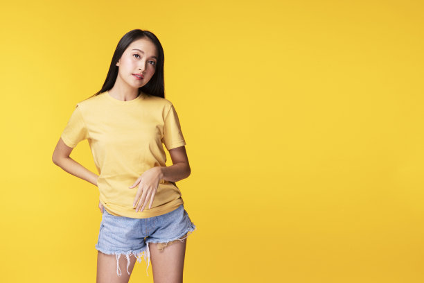 生活方式放松的概念。积极微笑的亚洲女性穿着休闲服装，双臂交叉站在孤立的黄色背景。图片下载