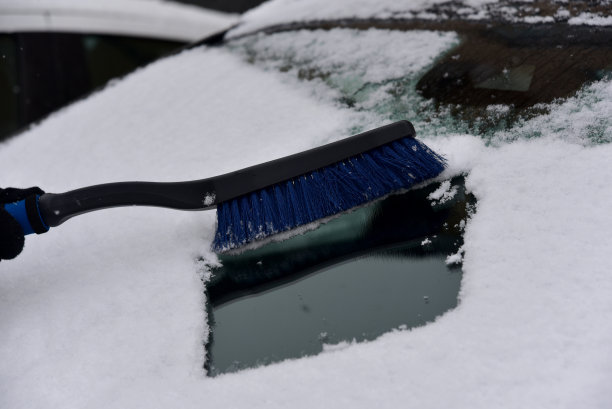 清除汽车挡风玻璃上的积雪。在冬天用雪把车窗擦干净。图片下载